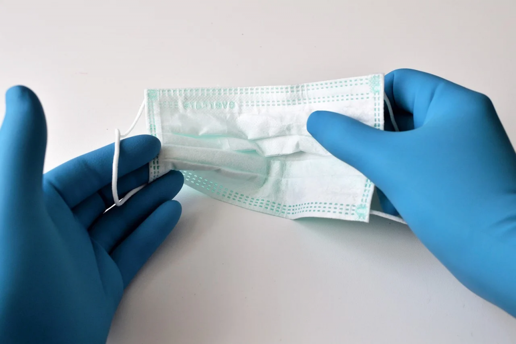 Deux mains gantées jouant avec un masque de procédure